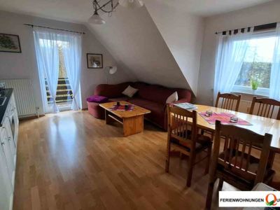 Im Wohnraum der Ferienwohnung 2 der Pesnion Quellenhof in Altenau finden Sie ein Ecksofa, TV, einen Esstisch und die Küchenzeile