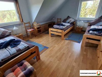 Im Schlafzimmer 2 der Ferienwohnung 2 der Pension Quellenhof in Altenau bietet 3 Einzelbetten mit Nachtischen, einen Kleiderschrank und Stühlen zur Kleiderablage.