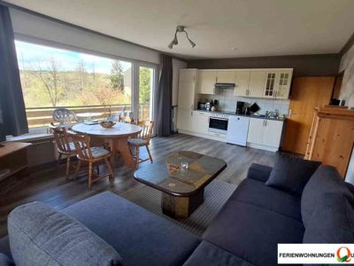 Der Wohnraum der Fereinwohnung 1 der Pension Quellenhof Altenau mit Blickwinkel auf Balkon und Küchenzeile