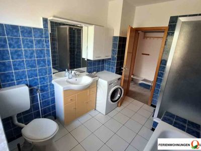 Das Badezimmer der Ferienwohnung 1 der Pension Quellenhof bietet Dusche, Badewanne, WC, Waschtisch mt Unterschrank, 2-türigem Hängeschrank und eine Waschmaschine.