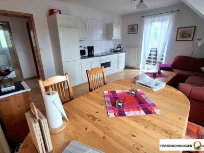 Der Blick vom Esstisch aus durch den Wohnraum in Richtung Balkontür. Der Wohnraum befindet sich in der Ferienwohnung 2 der Pension Quellenhof Altenau im Oberharz
