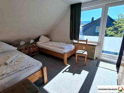Zwei Betten, Nachttische, STühle zur Kleiderablage, ein großer Kleiderschrank und Zugang zum Balkon, das Schlafzimmer 2 der Ferienwohnung 5 im Haus Celina der Pension Quellenhof Altenau lbietet alles für einen erholsamen Schlaf.