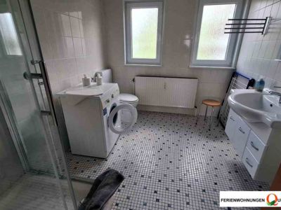 Größzügiges Badezimmer der Ferienwohnung 2 mit Dusche, WC, Waschtisch mit Unterschrank, Spiegel und Waschmaschine, zu finden im Angebot der Pension Quellenhof Altenau.